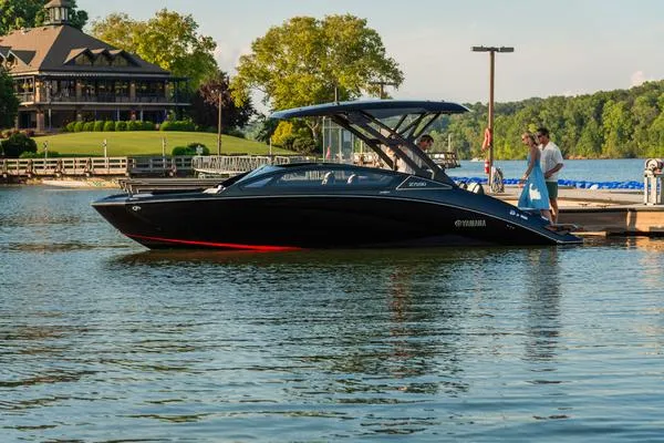Slide: The Image of 2025 Yamaha Boats 275 SD docked on a serene lake with lush greenery. - 7