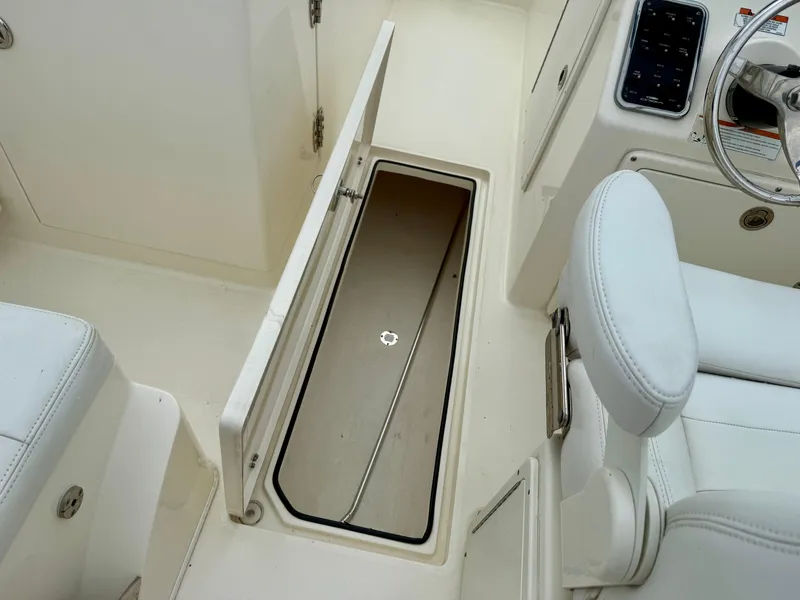 Slide: The Image of 2021 Cobia 220 Dual Console boat interior with open storage compartment. - 13
