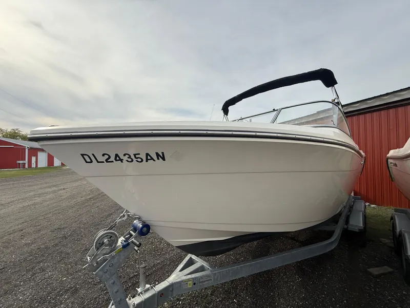 Slide: The Image of 2021 Cobia 220 Dual Console boat on trailer, parked near red building. - 3