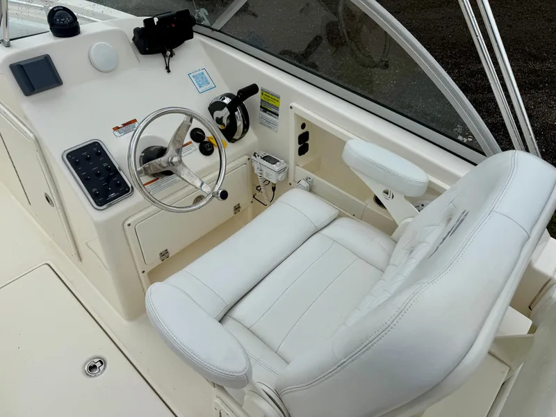 Slide: The Image of 2021 Cobia 220 Dual Console boat interior with steering wheel and white seating. - 6