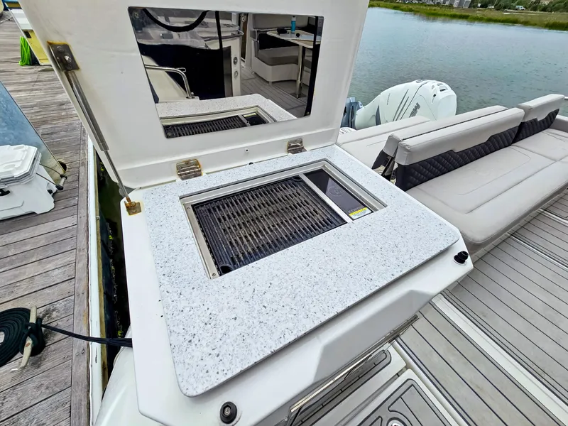 Slide: The Image of Aquila 36 Sport 2020 boat with outdoor grill and seating area by the water. - 30