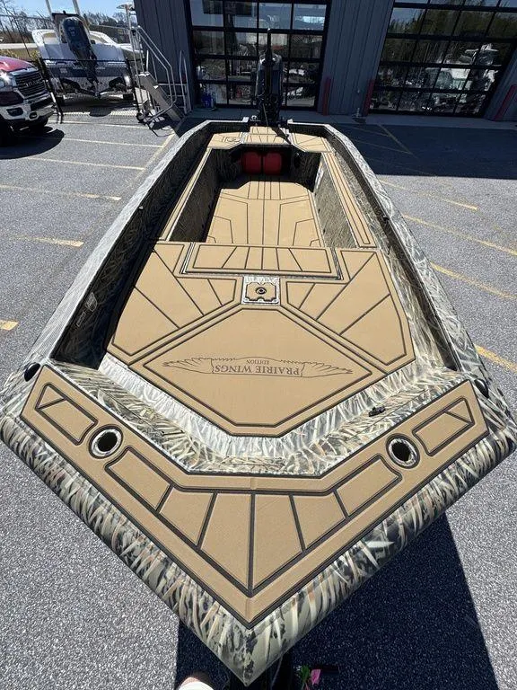 Slide: The Image of 2025 Tracker Grizzly 1650 T Prairie Wings Edition boat with camouflage design in a parking lot. - 14
