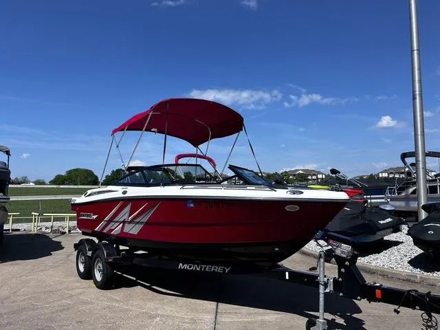 Slide: The Image of Red 2016 Monterey 196MS boat with canopy on trailer, parked outdoors under blue sky. - 2
