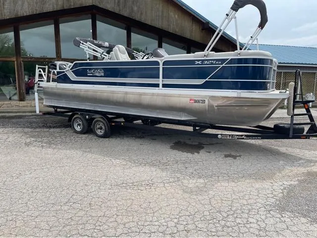Slide: The Image of 2018 SunCatcher X324RS pontoon boat on trailer, parked outside a building. - 1