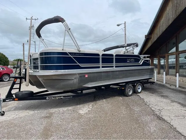Slide: The Image of 2018 SunCatcher X324RS pontoon boat on trailer, parked near a building. - 2
