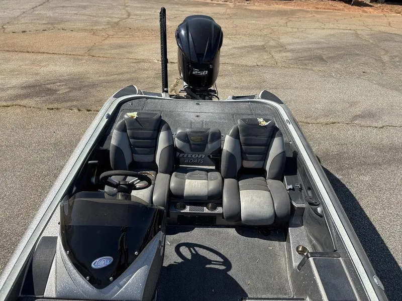 Slide: The Image of 2012 Triton 21 HP boat interior with seating and steering wheel, parked on pavement. - 17