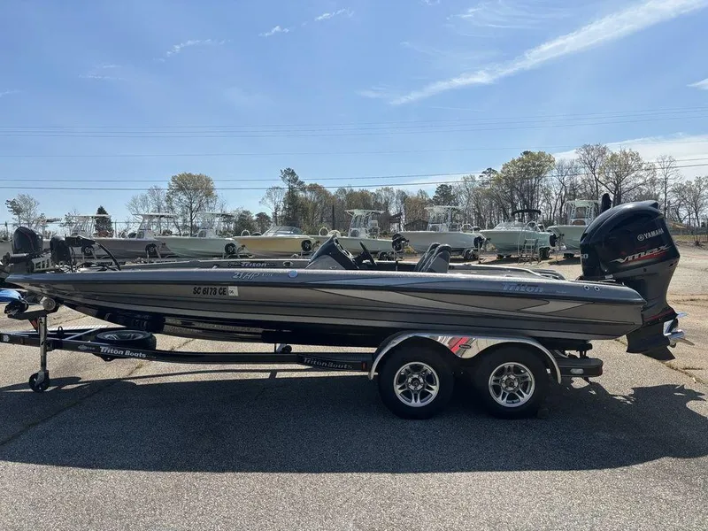 Slide: The Image of 2012 Triton 21 HP boat on trailer, parked outdoors under clear sky. - 8