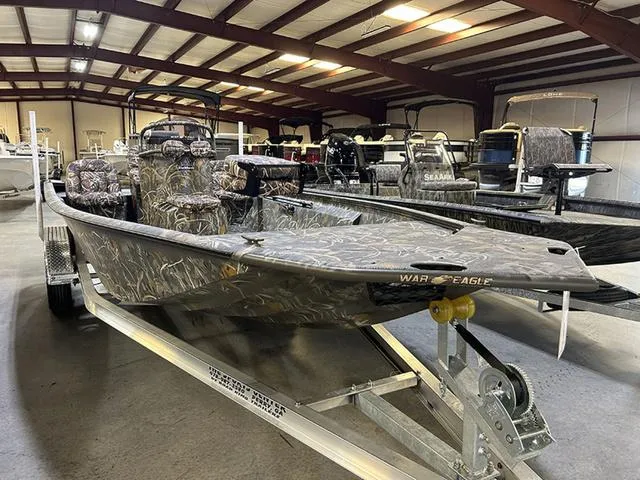 Slide: The Image of 2025 War Eagle 2170 Blackhawk CC boat in showroom, camo design, on trailer. - 1