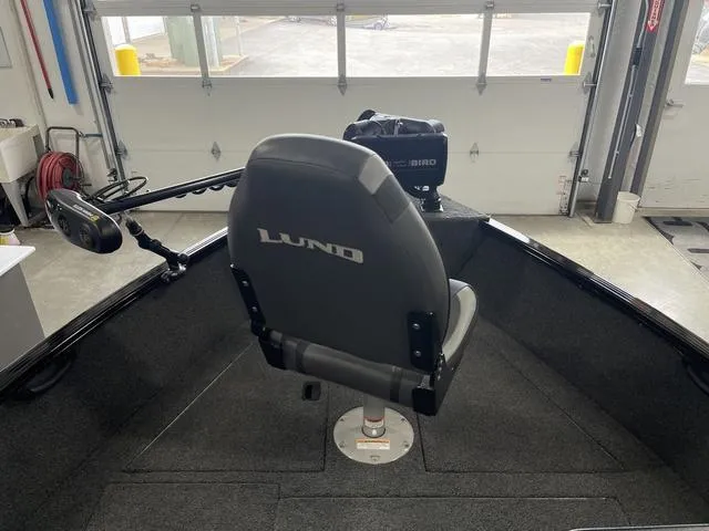Slide: The Image of 2021 Lund 1650 Rebel XL SS boat interior with swivel seat and motor in a garage. - 16