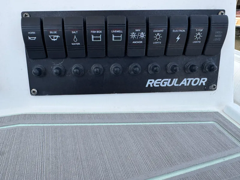 Slide: The Image of Control panel of a 2005 Regulator 23 Center Console boat with labeled switches. - 23
