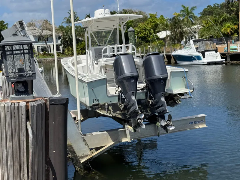 Slide: The Image of 2005 Regulator 23 Center Console boat on lift, dual outboard motors, dockside view. - 6