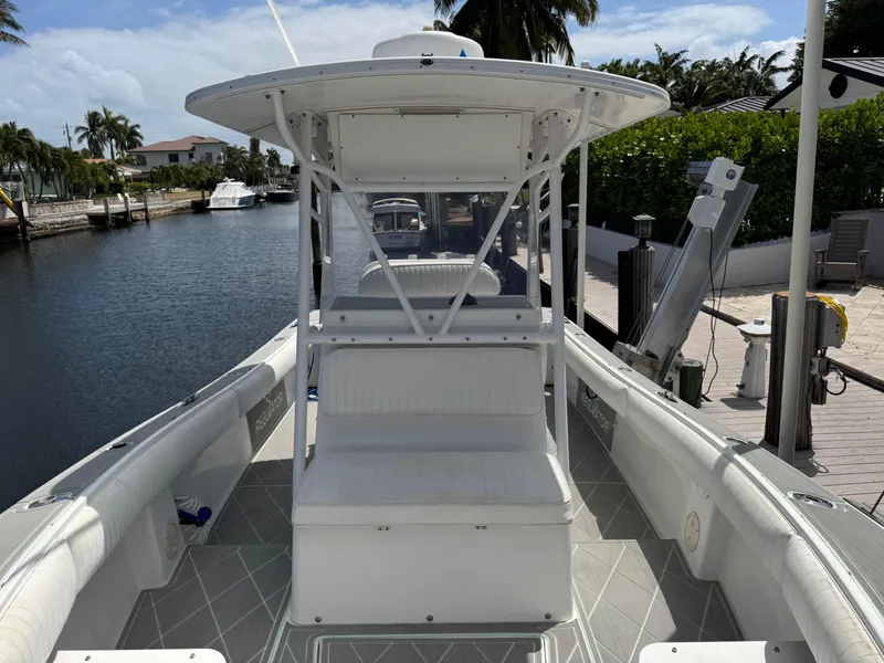 Slide: The Image of 2005 Regulator 23 Center Console boat docked by a canal, featuring spacious seating and canopy. - 9