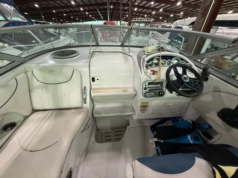 Slide: The Image of 2007 Crownline 250 CR boat interior with steering wheel and seating in a marina setting. - 10