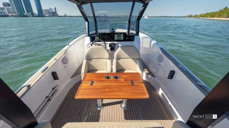 Slide: The Image of 2025 Rand Roamer boat interior with wooden table, open water view, and city skyline. - 11