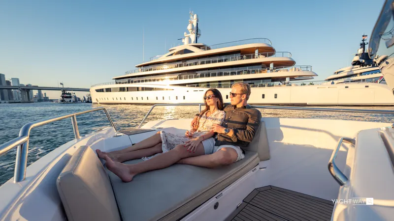 Slide: The Image of Couple relaxing on a Rand Roamer 2025 boat with a luxury yacht in the background. - 3