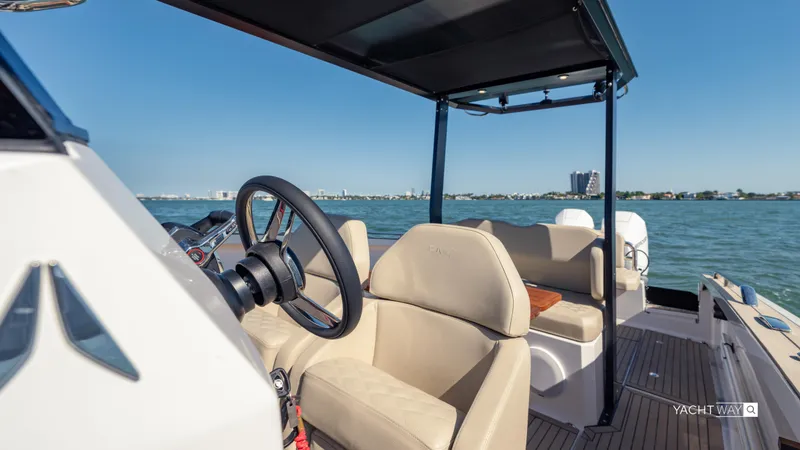 Slide: The Image of 2025 Rand Roamer boat interior with steering wheel, beige seating, and open water view. - 9