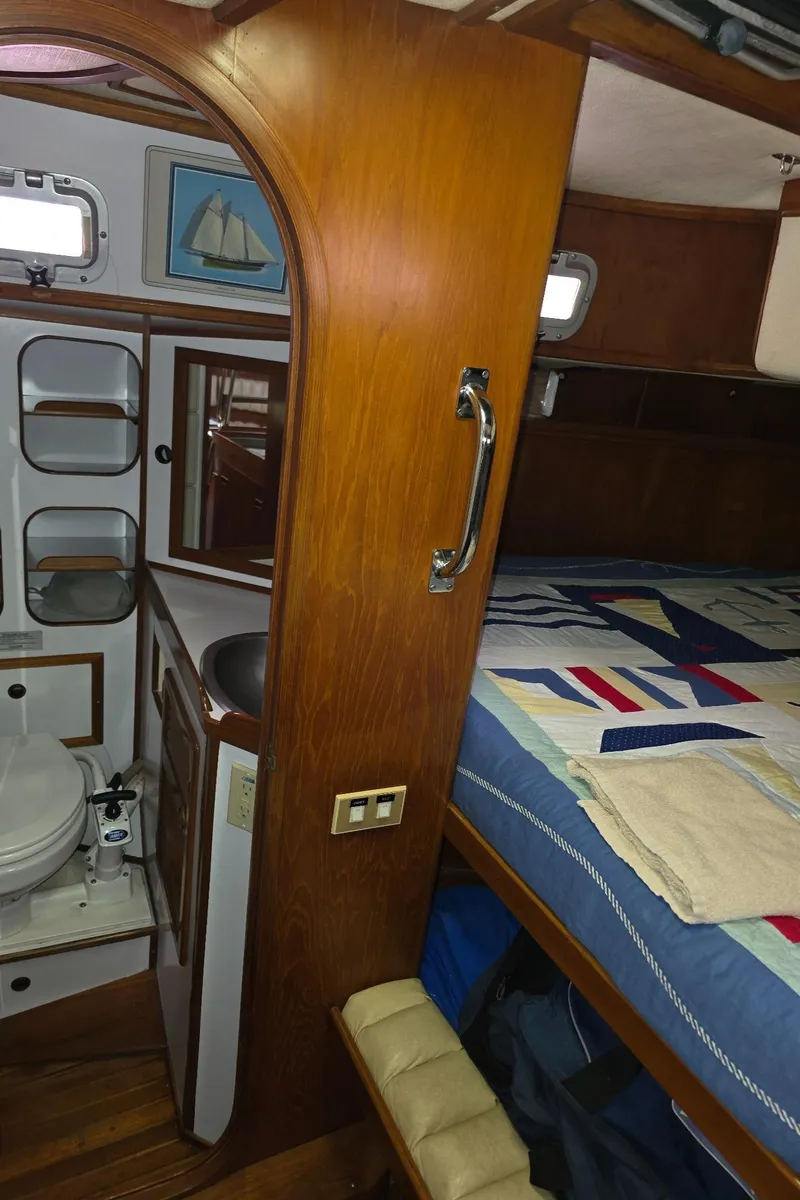 Slide: The Image of Cozy 1982 Stevens 40" yacht interior with wooden finish, featuring a compact bathroom and bed area. - 16