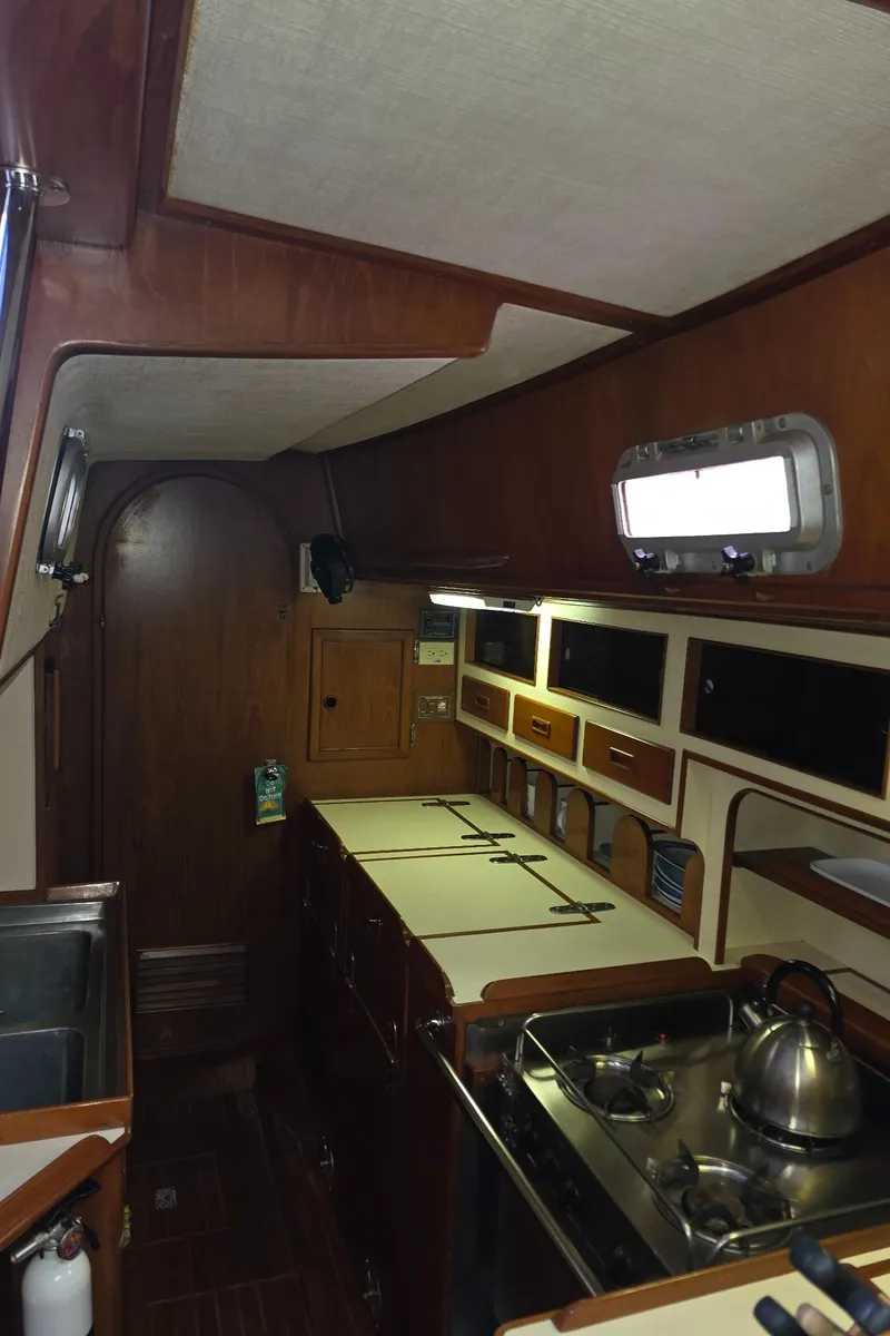 Slide: The Image of 1982 Stevens 40" yacht interior with wooden cabinetry, compact kitchen, and stainless steel appliances. - 22