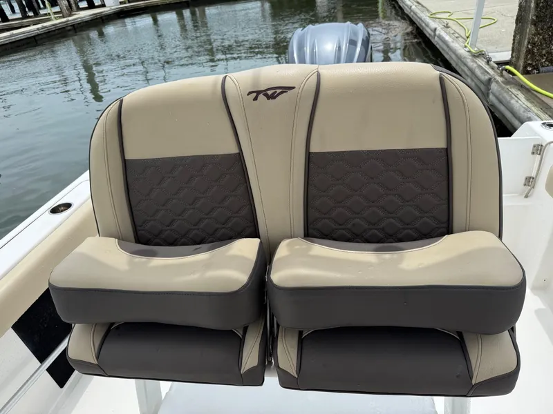 Slide: The Image of 2022 Tidewater 232 CC Adventure boat seats, beige and black, docked by water. - 13