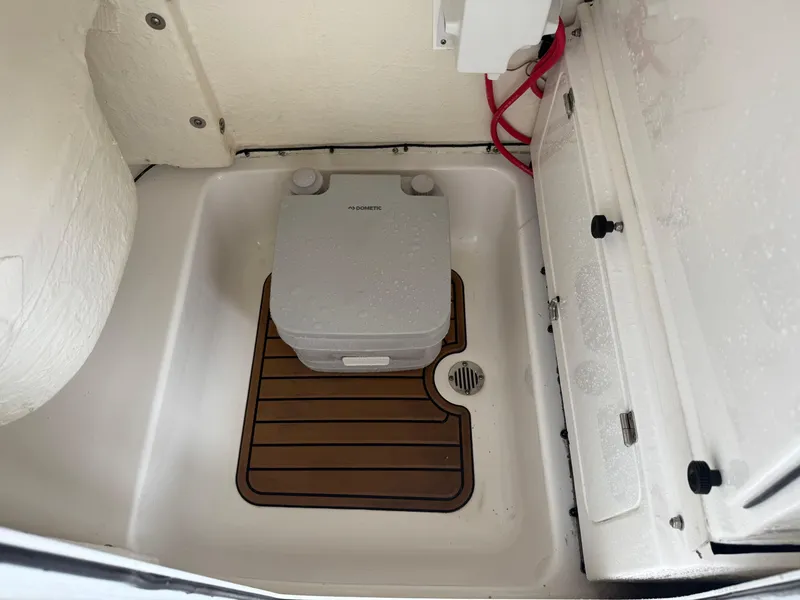 Slide: The Image of 2022 Tidewater 232 CC Adventure boat interior with portable toilet and wooden floor mat. - 16