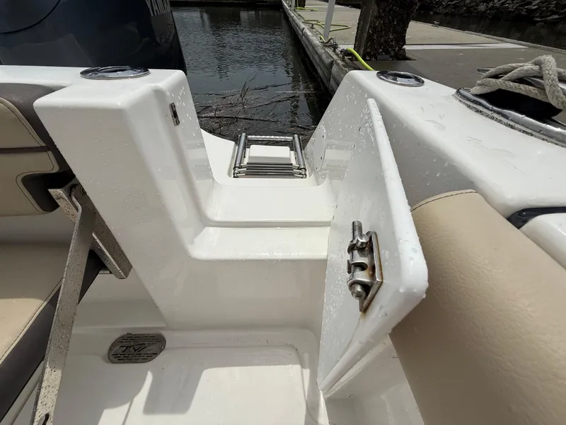 Slide: The Image of 2022 Tidewater 232 CC Adventure boat with open hatch and ladder near dock. - 23