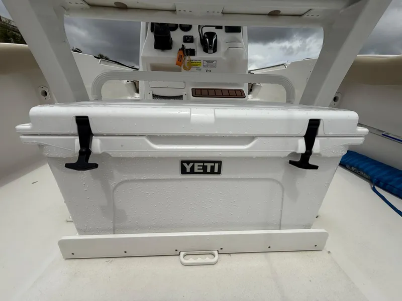 Slide: The Image of YETI cooler on 2022 Tidewater 232 CC Adventure boat deck, under cloudy sky. - 27
