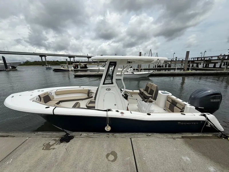 Slide: The Image of 2022 Tidewater 232 CC Adventure boat docked at marina under cloudy sky. - 5