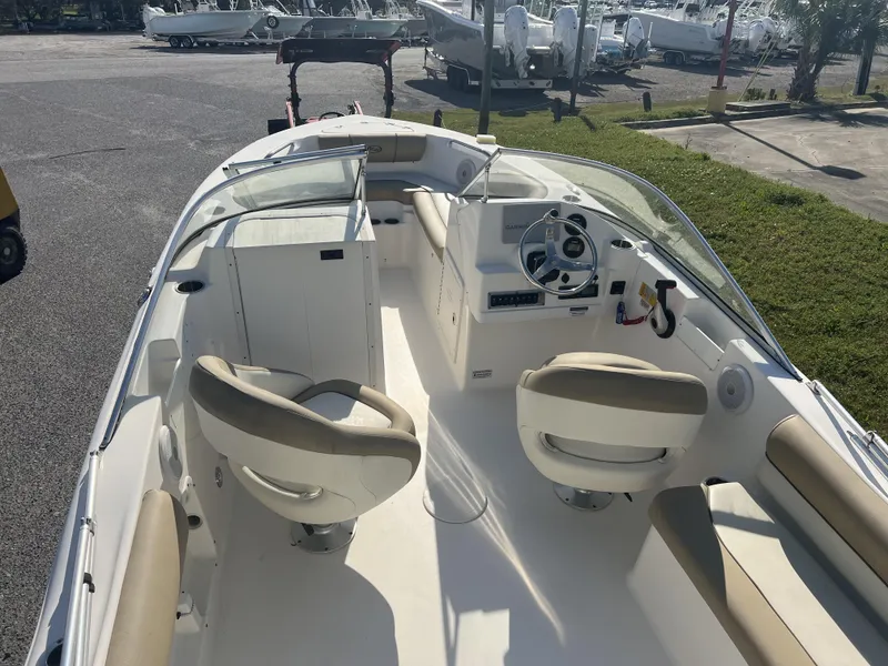Slide: The Image of 2020 Key West 203DFS boat interior with seating and steering wheel, parked on pavement. - 7