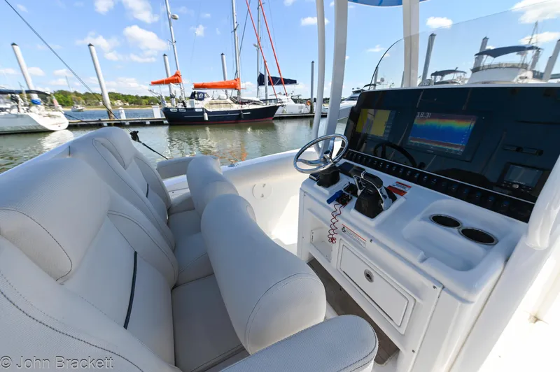 Slide: The Image of 2014 Sea Hunt Gamefish 30 boat interior with helm, seats, and marina view. - 10