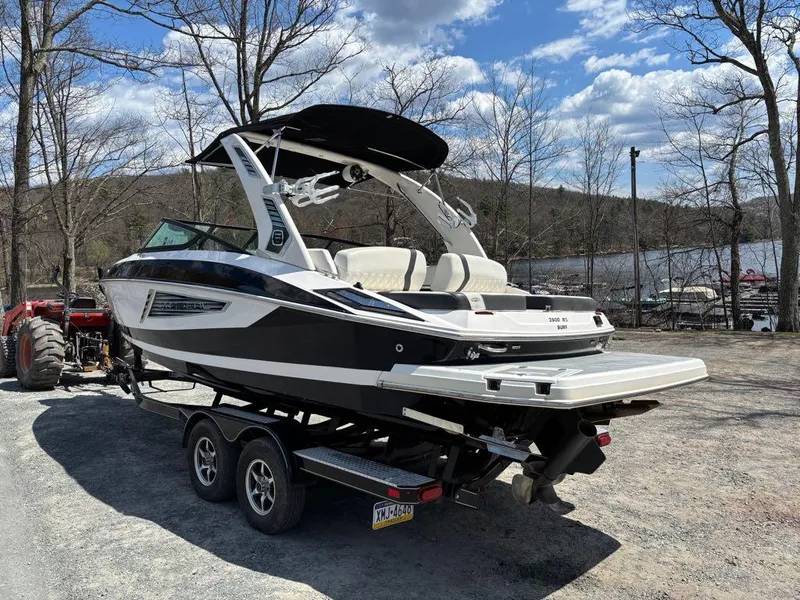 Slide: The Image of 2019 Regal 25 RX Surf boat on trailer near lake, under clear sky. - 8