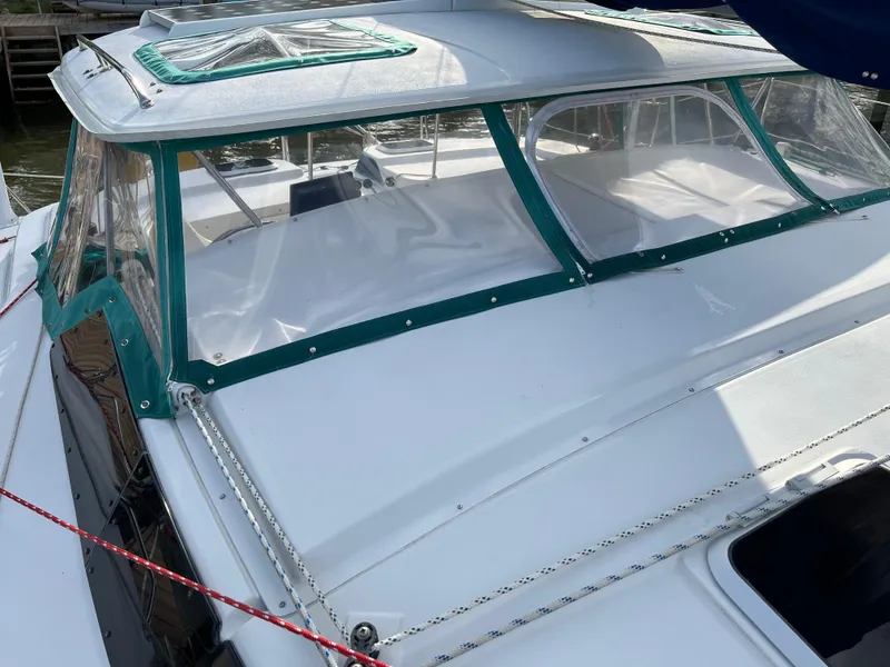 Slide: The Image of 2003 PDQ 32 boat with green-trimmed canopy and clear windows, docked in sunlight. - 21