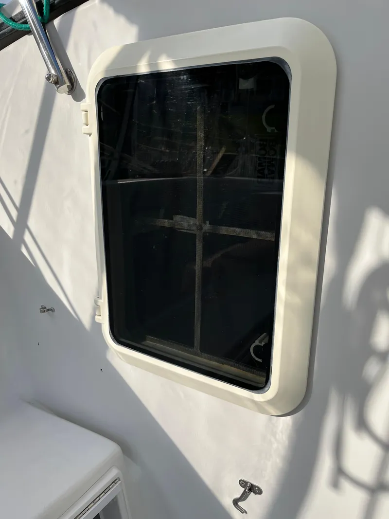 Slide: The Image of Boat window on a 2003 PDQ 32, featuring a white frame and dark glass. - 23