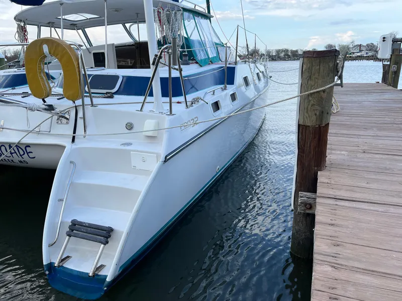 Slide: The Image of PDQ 32 catamaran docked at marina, featuring a white hull and blue accents. - 27