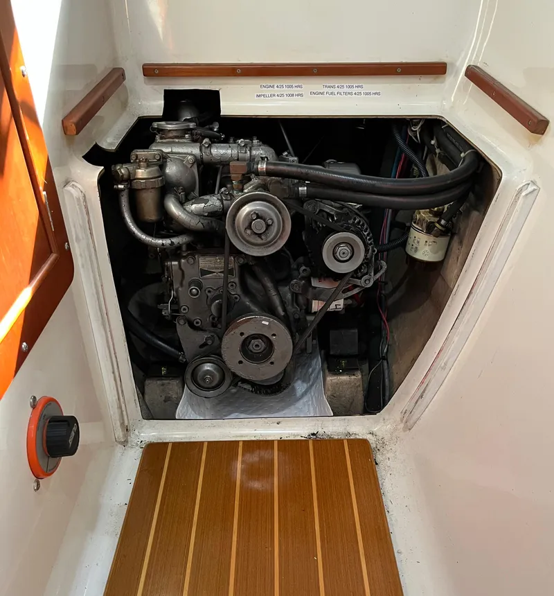 Slide: The Image of Engine compartment of a 2003 PDQ 32 boat, showcasing mechanical components and wooden flooring. - 36