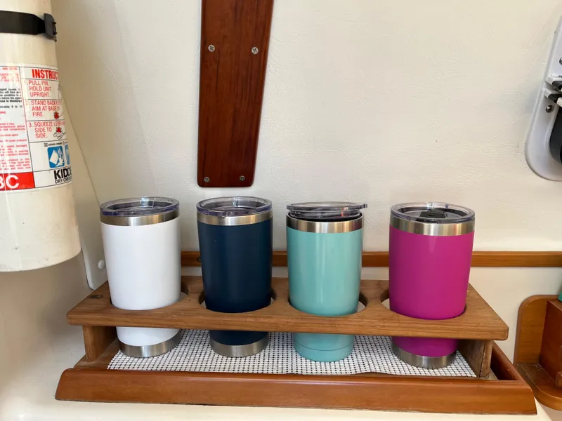 Slide: The Image of Colorful tumblers in wooden holder on PDQ 32 boat, next to fire extinguisher. - 49