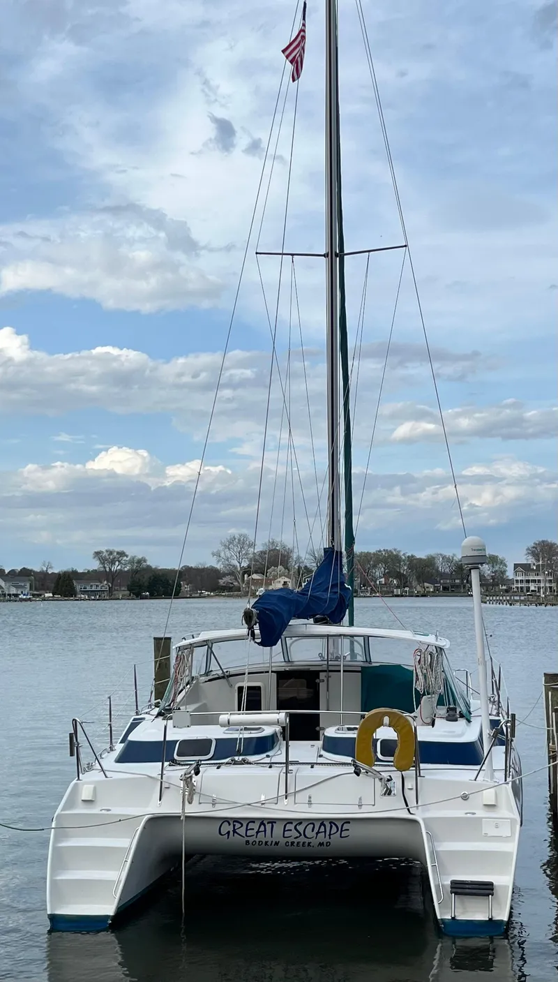 Slide: The Image of 2003 PDQ 32 catamaran "Great Escape" docked on a calm lake under a cloudy sky. - 7