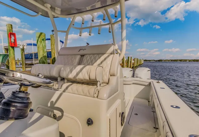 Slide: The Image of 2017 Yellowfin 36 Offshore boat interior with helm, docked by the water under a blue sky. - 13