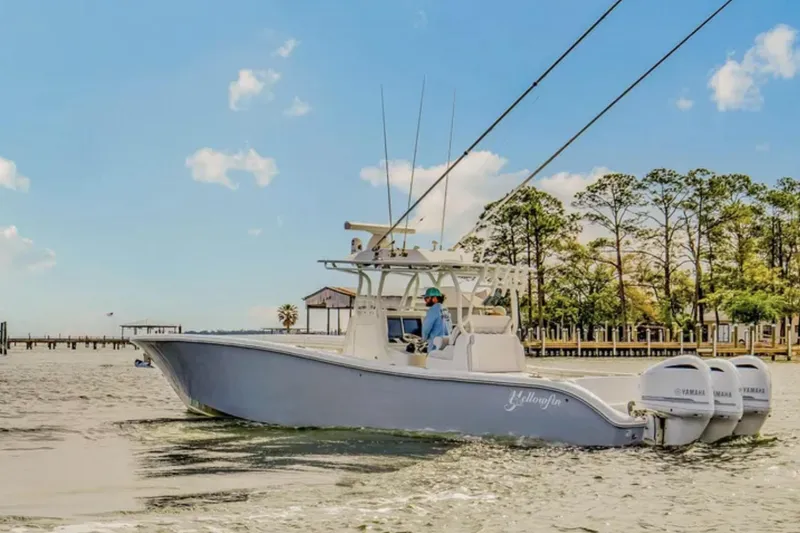 Slide: The Image of 2017 Yellowfin 36 Offshore boat cruising on a sunny day near a tree-lined shore. - 7