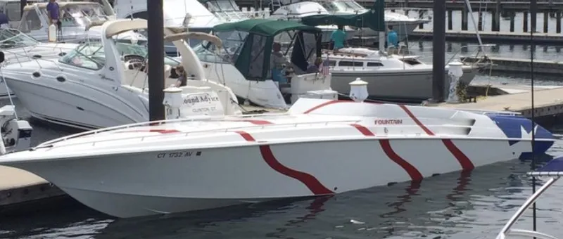 Slide: The Image of 1998 Fountain 42 Lightning speedboat docked, featuring sleek design and red stripes. - 14