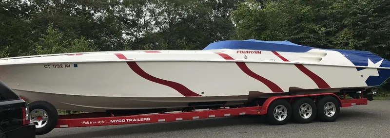 Slide: The Image of 1998 Fountain 42 Lightning speedboat on trailer, featuring red and white design, parked outdoors. - 16