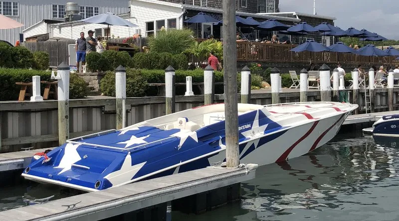 Slide: The Image of 1998 Fountain 42 Lightning boat with star-spangled design docked near waterfront restaurant. - 5