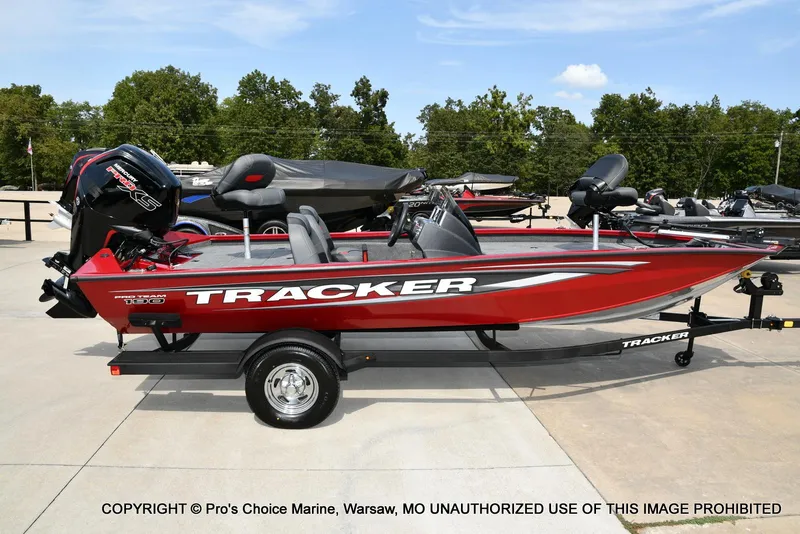 Slide: The Image of 2025 Tracker Pro Team 190 TX boat in red, parked on a trailer outdoors. - 19