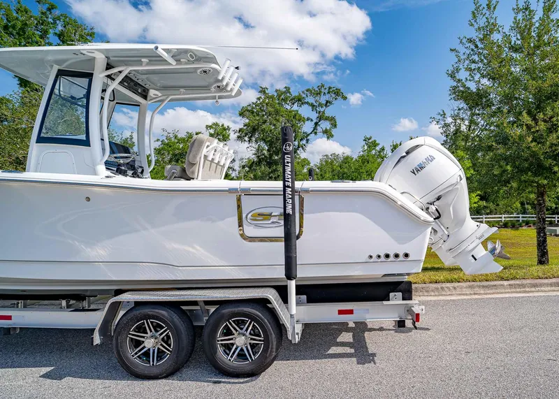 Slide: The Image of 2025 Sea Hunt Gamefish 25 boat on trailer with Yamaha engine, parked on a sunny day. - 3