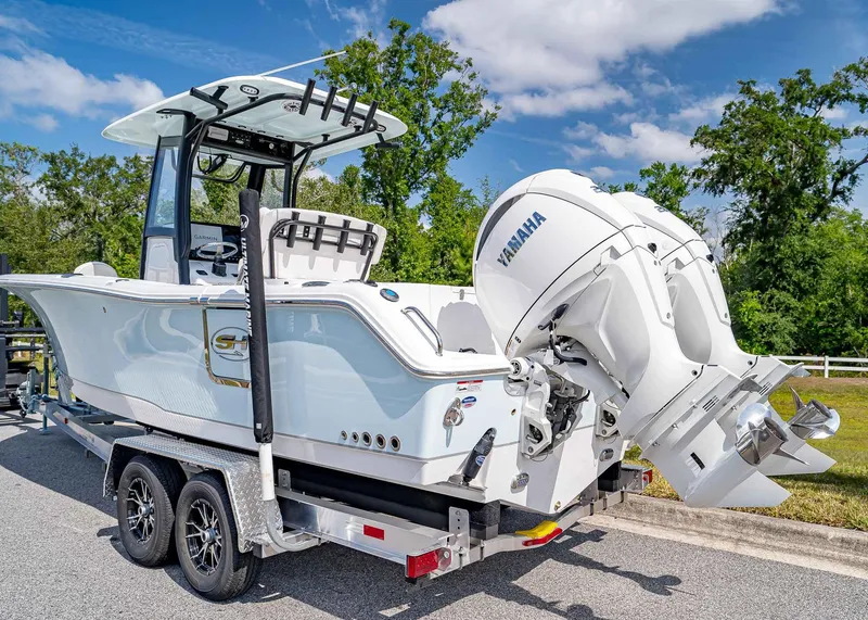 Slide: The Image of 2025 Sea Hunt Gamefish 25 boat on trailer with Yamaha engines, parked outdoors. - 4