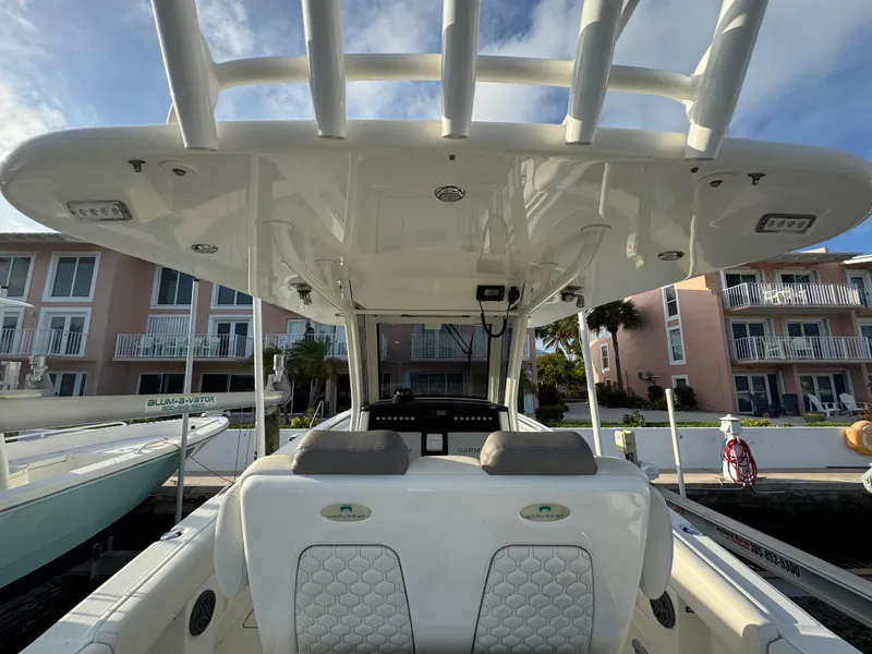 Slide: The Image of 2018 World Cat 280 CC-X boat interior with seating and helm, docked near waterfront homes. - 10
