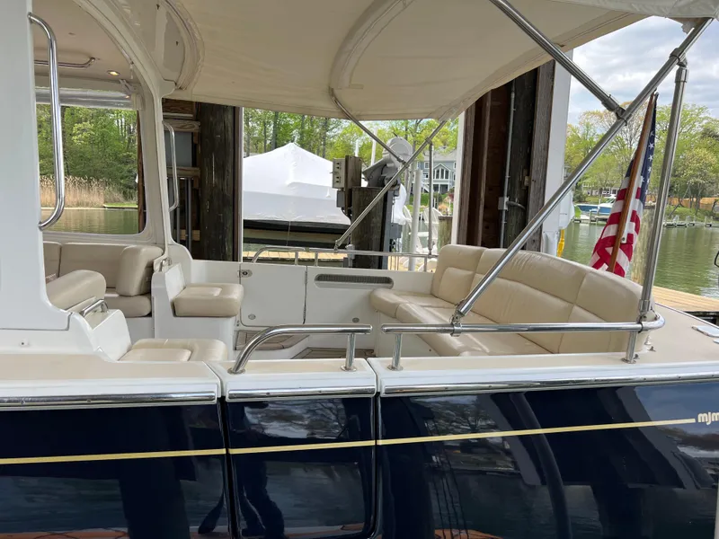Slide: The Image of 2011 MJM 36Z boat with beige seating and canopy, docked near a waterfront. - 14