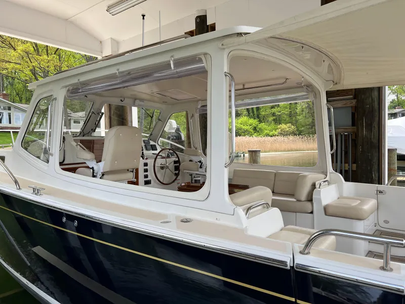 Slide: The Image of 2011 MJM 36Z boat with enclosed cockpit and seating, docked in a serene setting. - 19