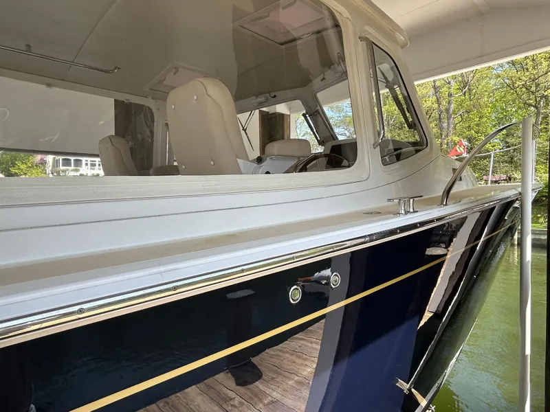 Slide: The Image of 2011 MJM 36Z boat with sleek design, docked near lush greenery. - 2