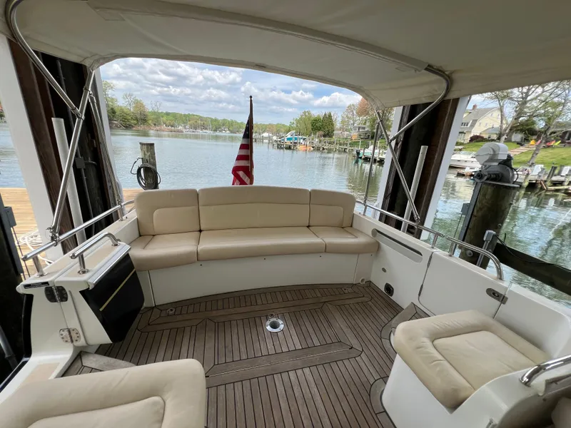 Slide: The Image of MJM 36Z 2011 boat interior with beige seating, wooden deck, and scenic waterfront view. - 32