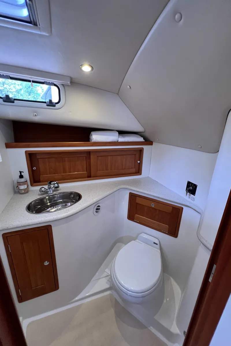 Slide: The Image of 2011 MJM 36Z boat bathroom with sink, toilet, and wooden cabinets. - 34